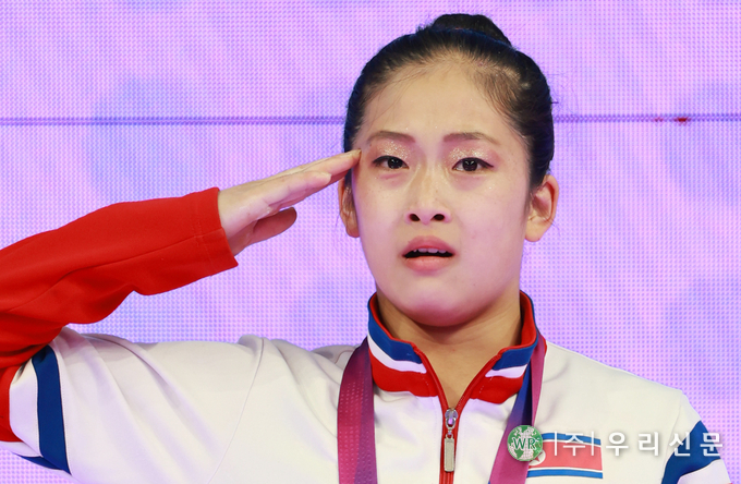 한 안창옥이 28일 중국 항저우 황룽 스포츠센터 체육관에서 열린 2022 항저우 아시안게임 여자 기계체조 도마 결선에서 금메달을 차지한 뒤 시상식에서 인공기가 게양되고 국가가 연주되자 눈물을 글썽이며 거수경례하고 있다