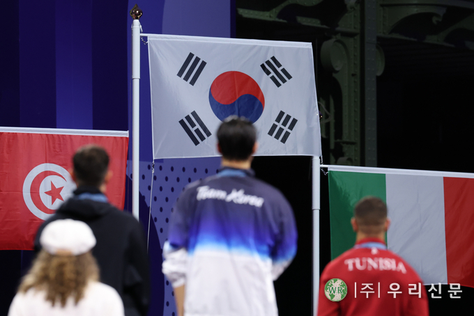 = 27일(현지시간) 프랑스 파리 그랑 팔레에서 열린 2024 파리올림픽 펜싱 남자 사브르 시상식에서 금메달을 차지한 오상욱 뒤로 태극기가 게양되고 있다. (사진/연합)